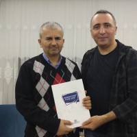 Yalova Üniversitesi Öğretim Üyesi Dr. Yunus Özen, Dr. Hasan Dermenci’ye platformun kitabını takdim ederken